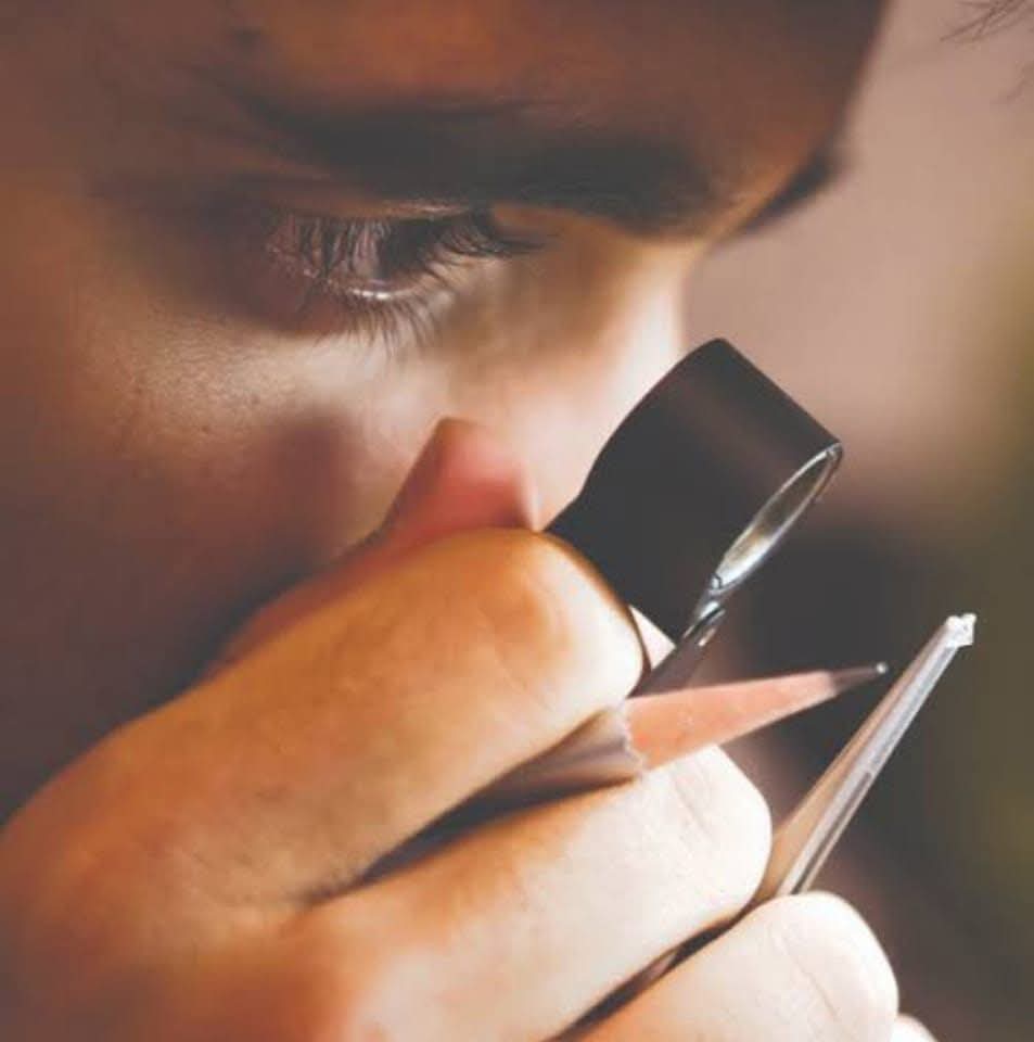 Close-up of a person examining a gemstone with a jeweler's loupe